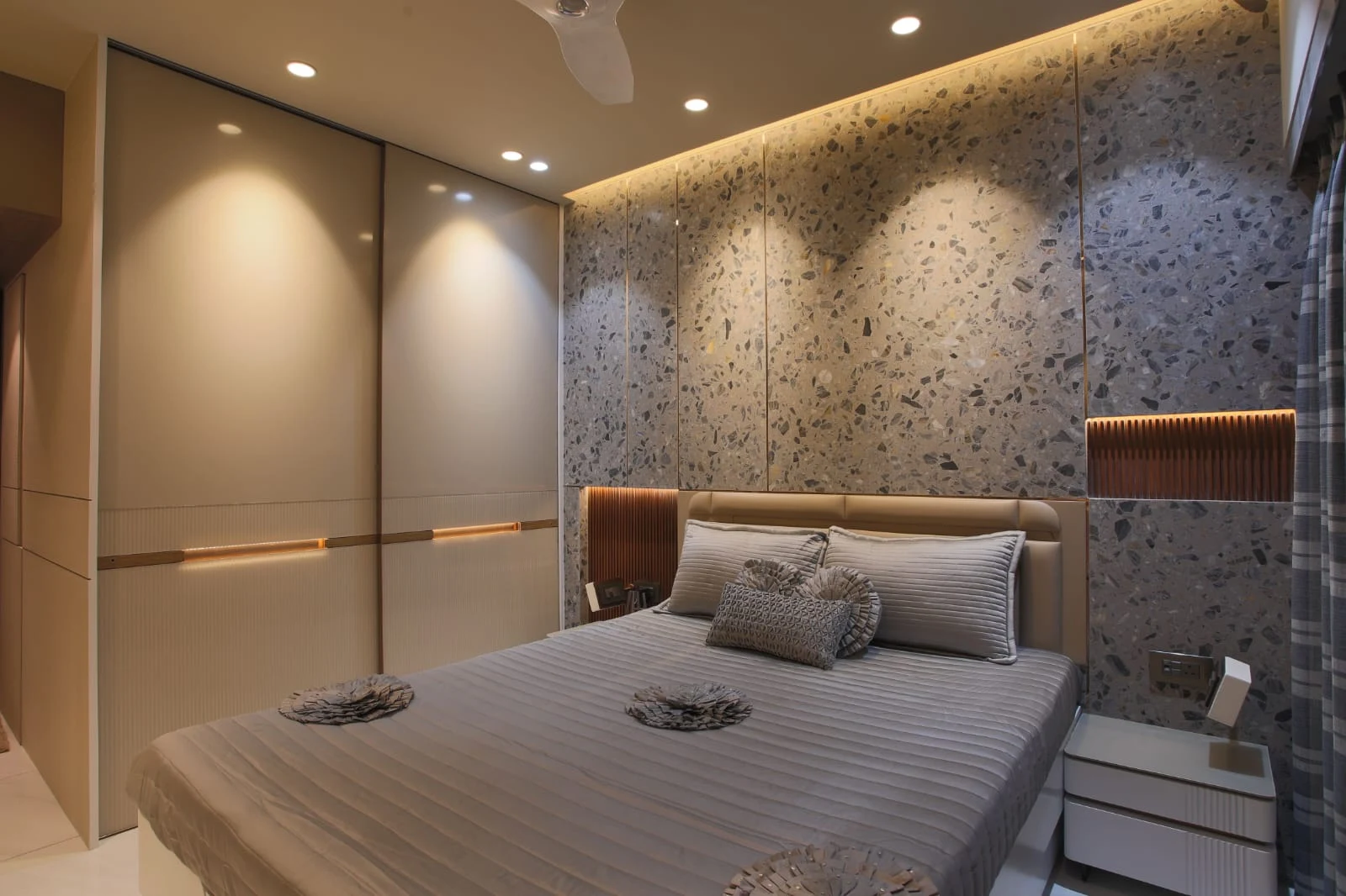 Bedroom corner with a wood-and-stone accent wall and a built-in sliding wardrobe fitted into the alcove
