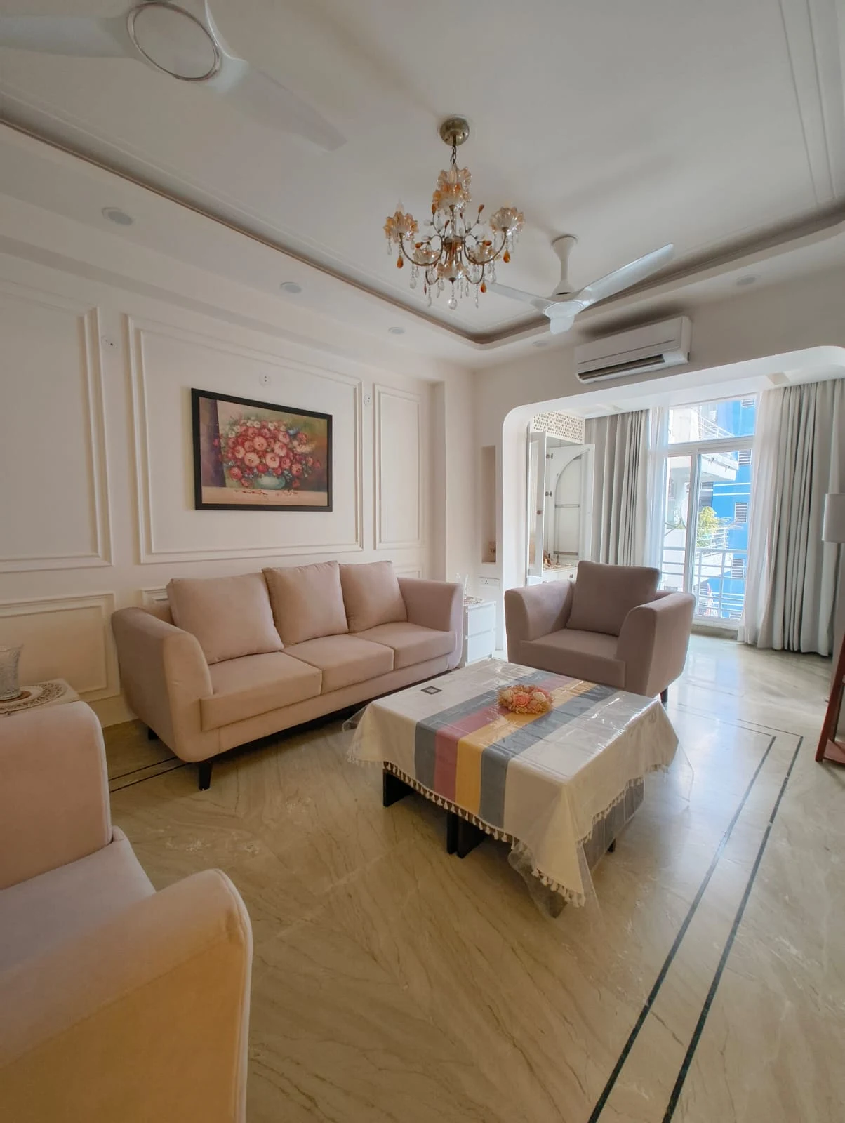 Living room seating layout by Livibi with a blush-toned sofa set and balcony access