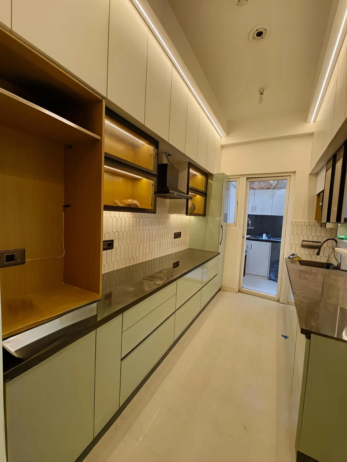 Narrow galley-style modular kitchen by Livibi with off-white cabinetry, floating wood-tone display boxes and hexagonal tile backsplash