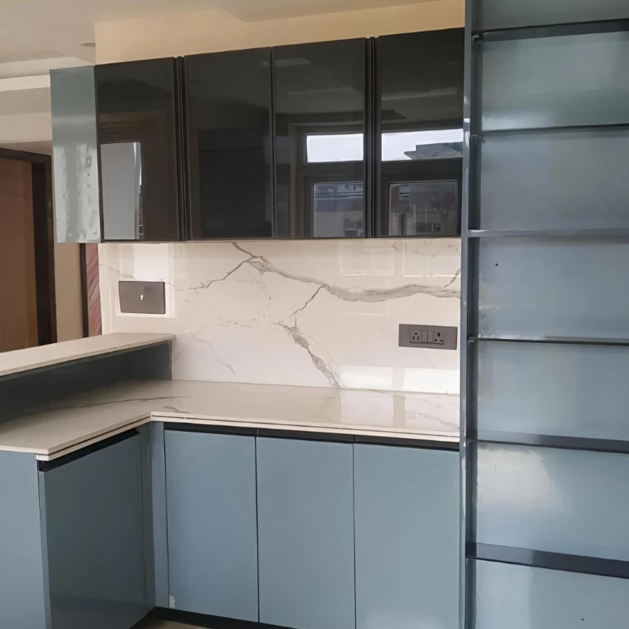 Blue-grey glossy modular kitchen by Livibi with a white marble countertop and a tall mirrored open-shelf storage unit